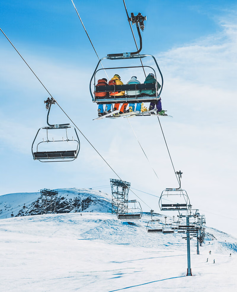 Skiiers on a chairlift ascending a snowy mountain during luxury Italy family trips.