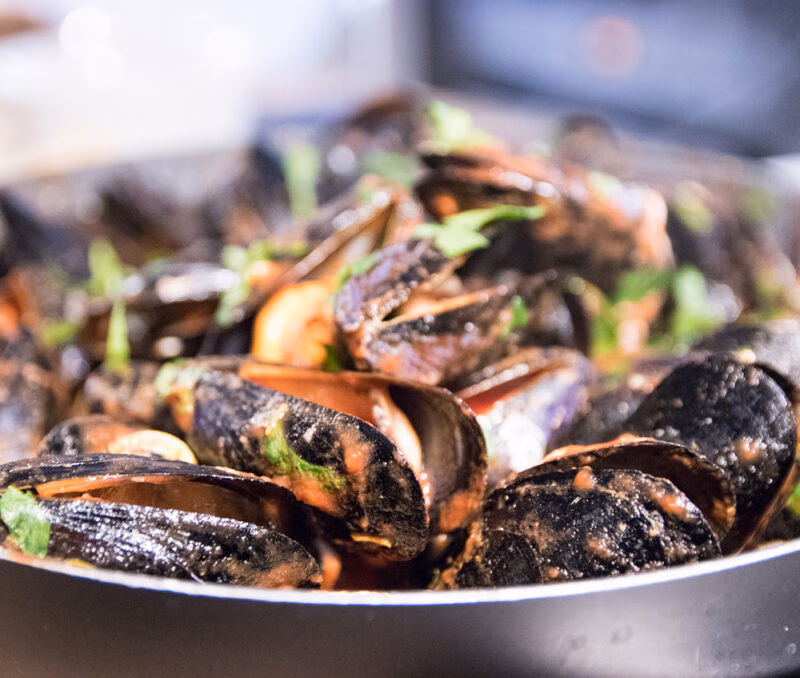 Close-up of cooked mussels in shells with herbs, representing the cuisine of luxury Croatia tours.