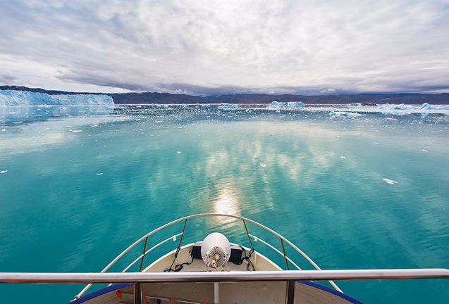 View from a boat bow of turquoise water and distant glaciers on luxury Polar trips.
