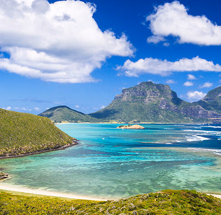 Tropical lagoon with turquoise water and green mountains for luxury Australasia tours.