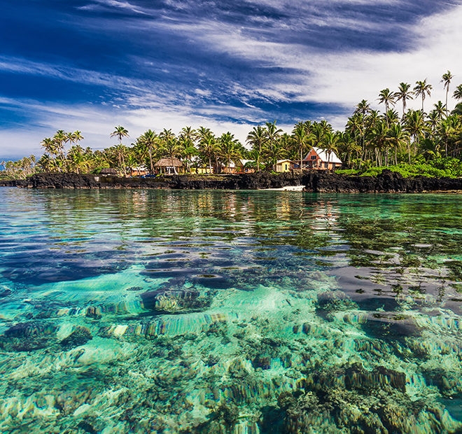 Transparent turquoise water in front of a tropical beach resort for luxury Australasia trips.