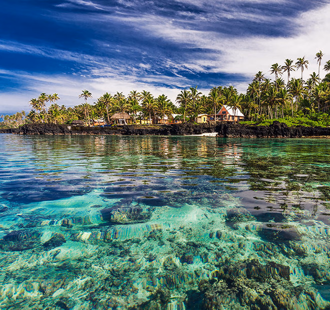 Transparent turquoise water in front of a tropical beach resort for luxury Australasia trips.