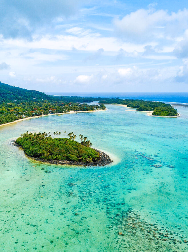 Aerial view of tropical islands and turquoise coral reefs on luxury Australasia holidays.