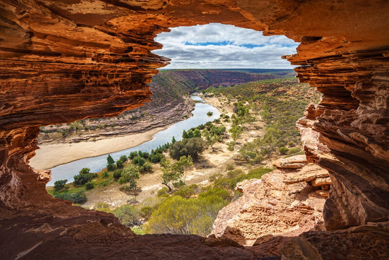 View of a river through a natural rock window formation during luxury Australasia holidays.