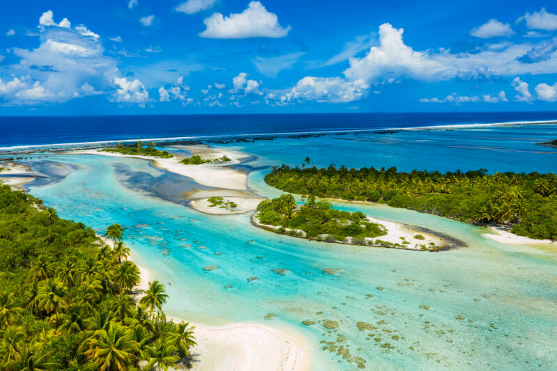 Aerial view of tropical islands and turquoise lagoons ideal for luxury Australasia holidays.