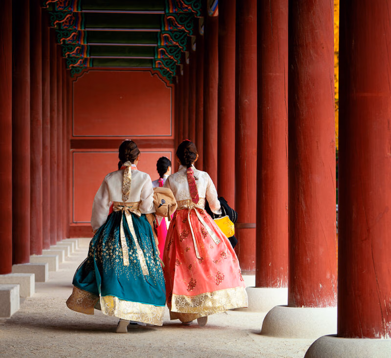 Women in traditional Hanbok walking through a palace during luxury South Korea trips.