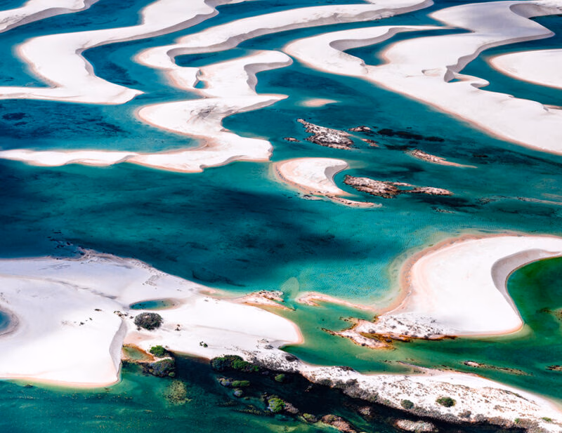 Aerial view of undulating white sand dunes interspersed with bright turquoise water lagoons. luxury Brazil tours.