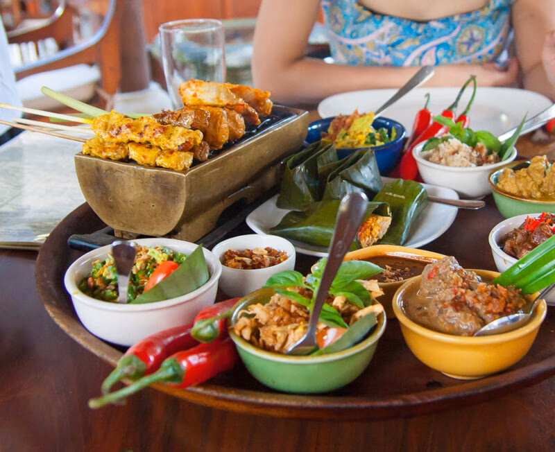 A spread of traditional Indonesian food and satay sticks for luxury Bali holidays.