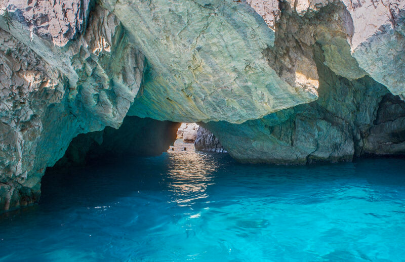 Interior of a sea cave with glowing blue water on luxury Amalfi Coast tours.