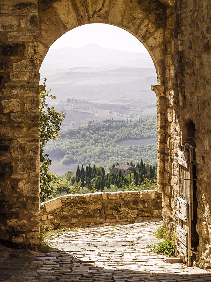 A stone archway framing a scenic view of the Tuscan landscape, perfect for luxury Tuscany vacations.