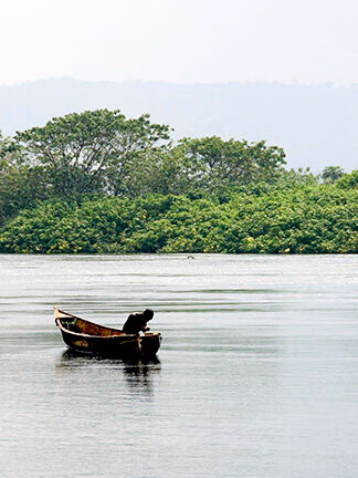 A person in a small boat on a quiet lake during luxury Africa honeymoon vacations.