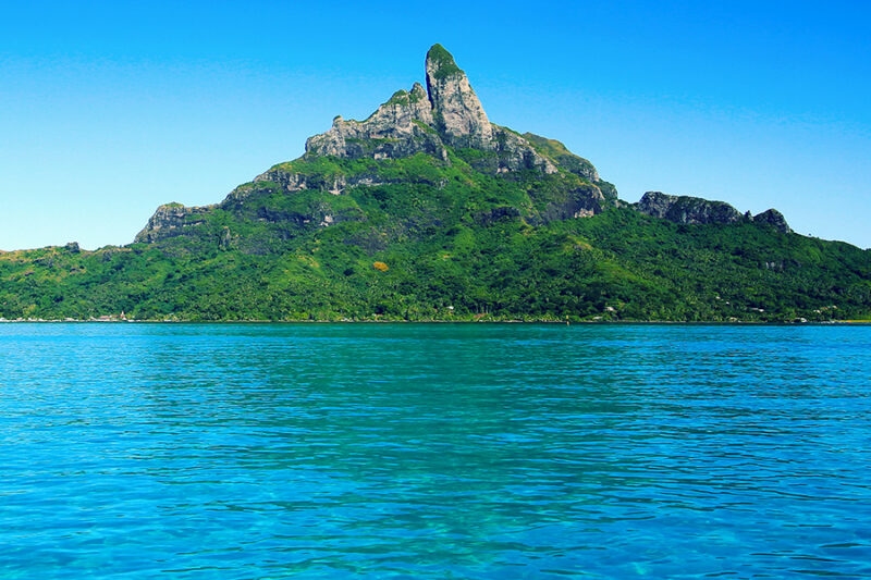 The iconic Mount Otemanu rising from blue sea water during luxury French Polynesia holidays.