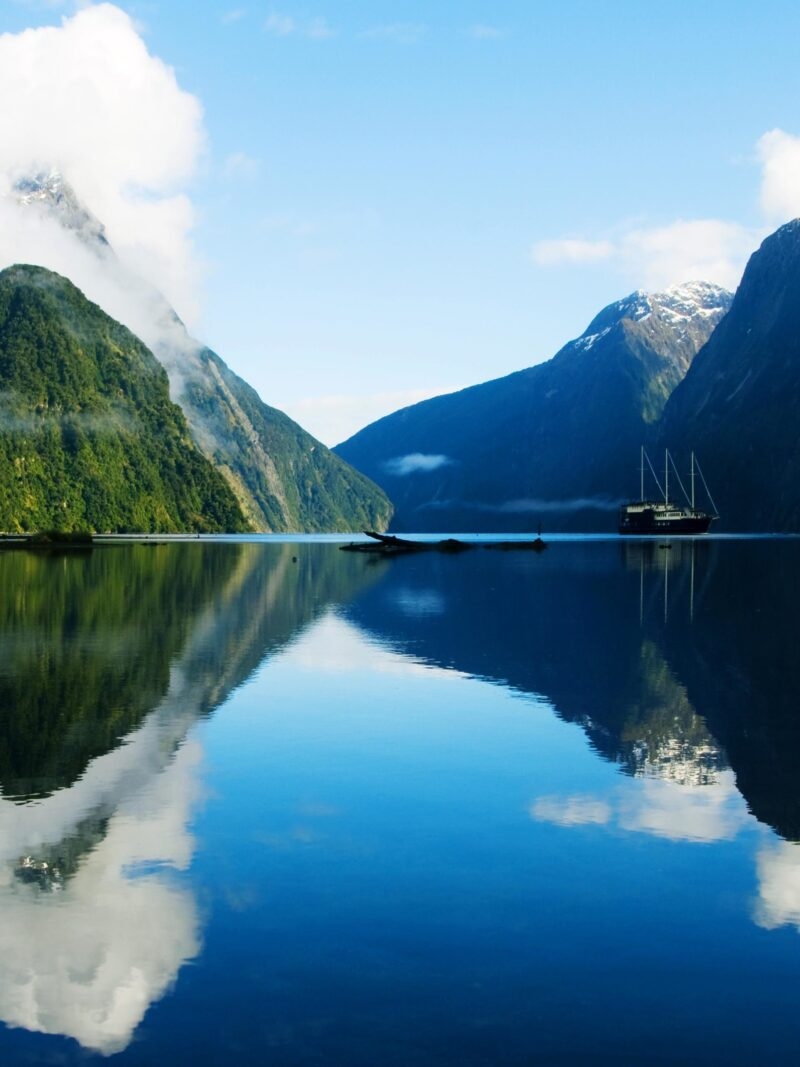 Ship on a calm fjord with mountain reflections during luxury grand tours and safaris.