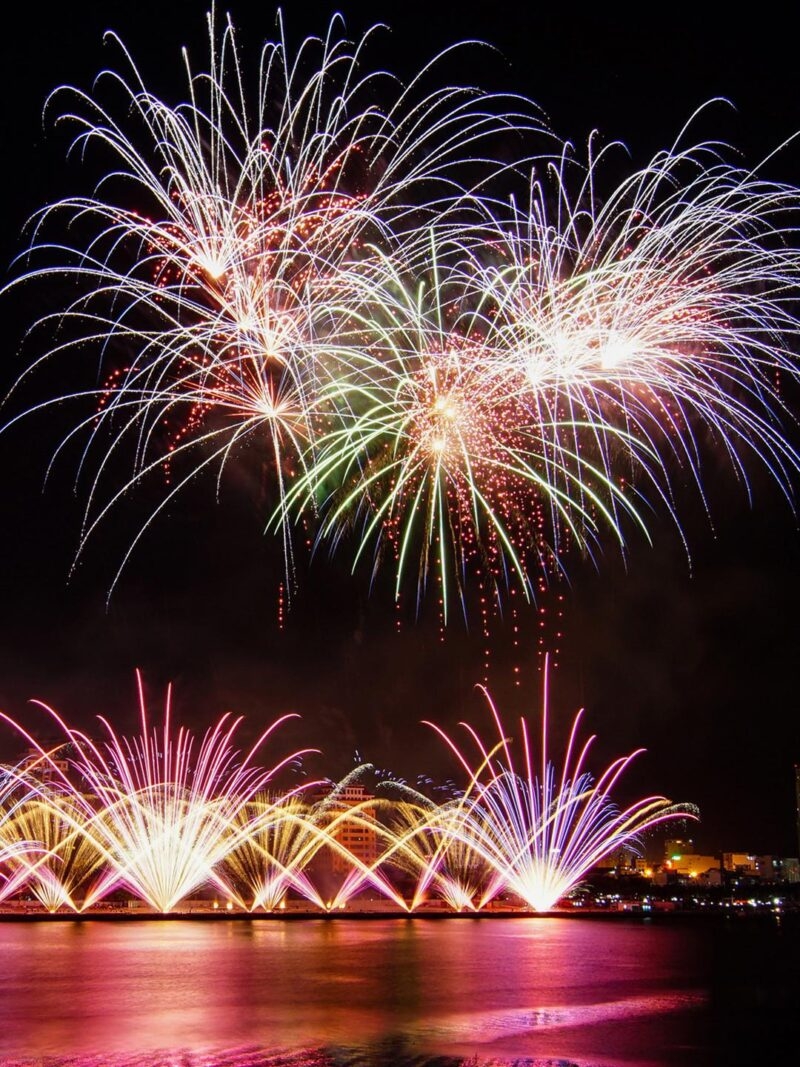 Colorful fireworks display over a city river during luxury special occasion tours.