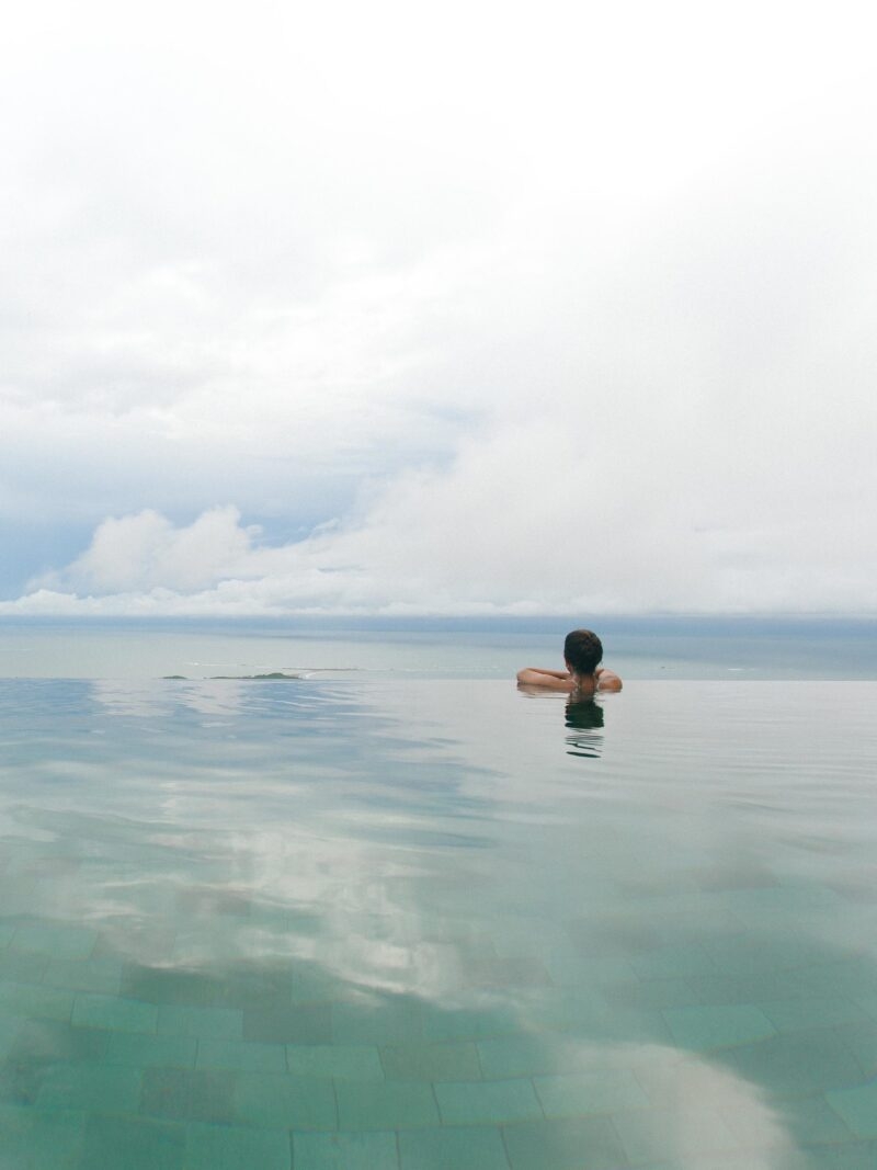 A woman looking out over the edge of an infinity pool towards the sea