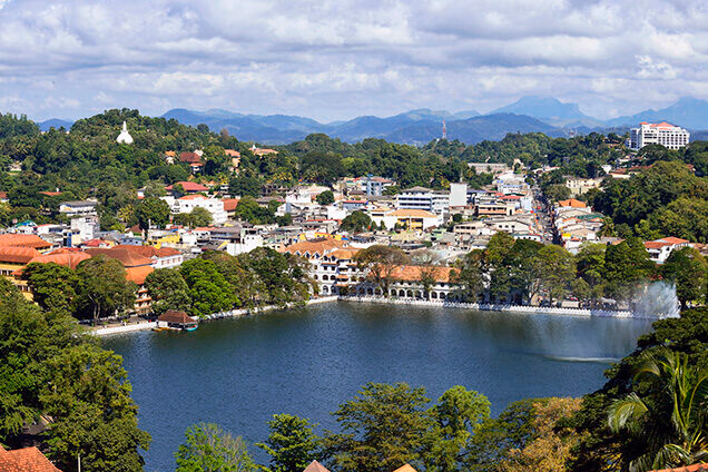 Aerial view of a city lake surrounded by white buildings and green hills on luxury Indian Subcontinent tours.