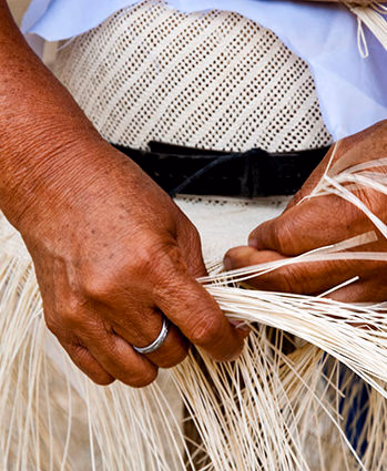 Close up of hands weaving a straw hat during luxury culture tours.