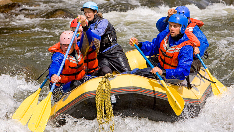 A group of people navigate river rapids in a yellow raft during luxury Latin America family holidays.