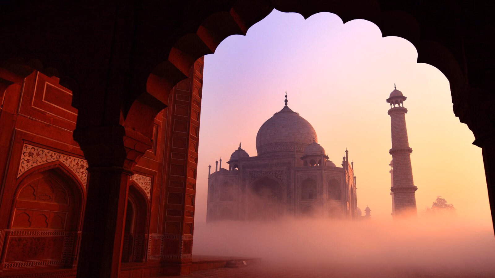 View of the Taj Mahal through a red sandstone archway during luxury Indian Subcontinent holidays.