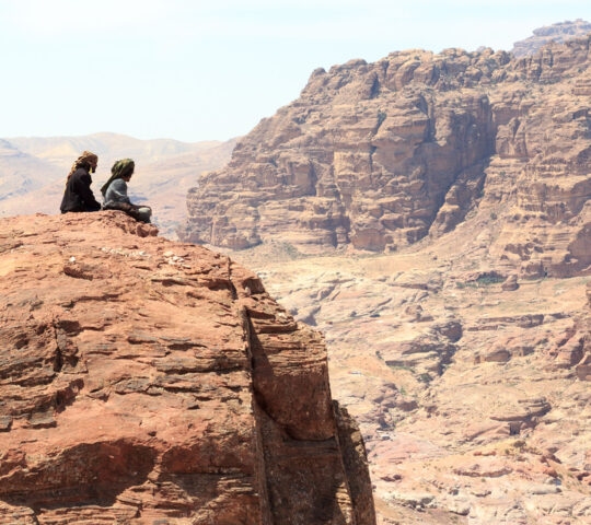 Bedouins sitting on rock at High place of sacrifice in ancient city of Petra in Jordan
