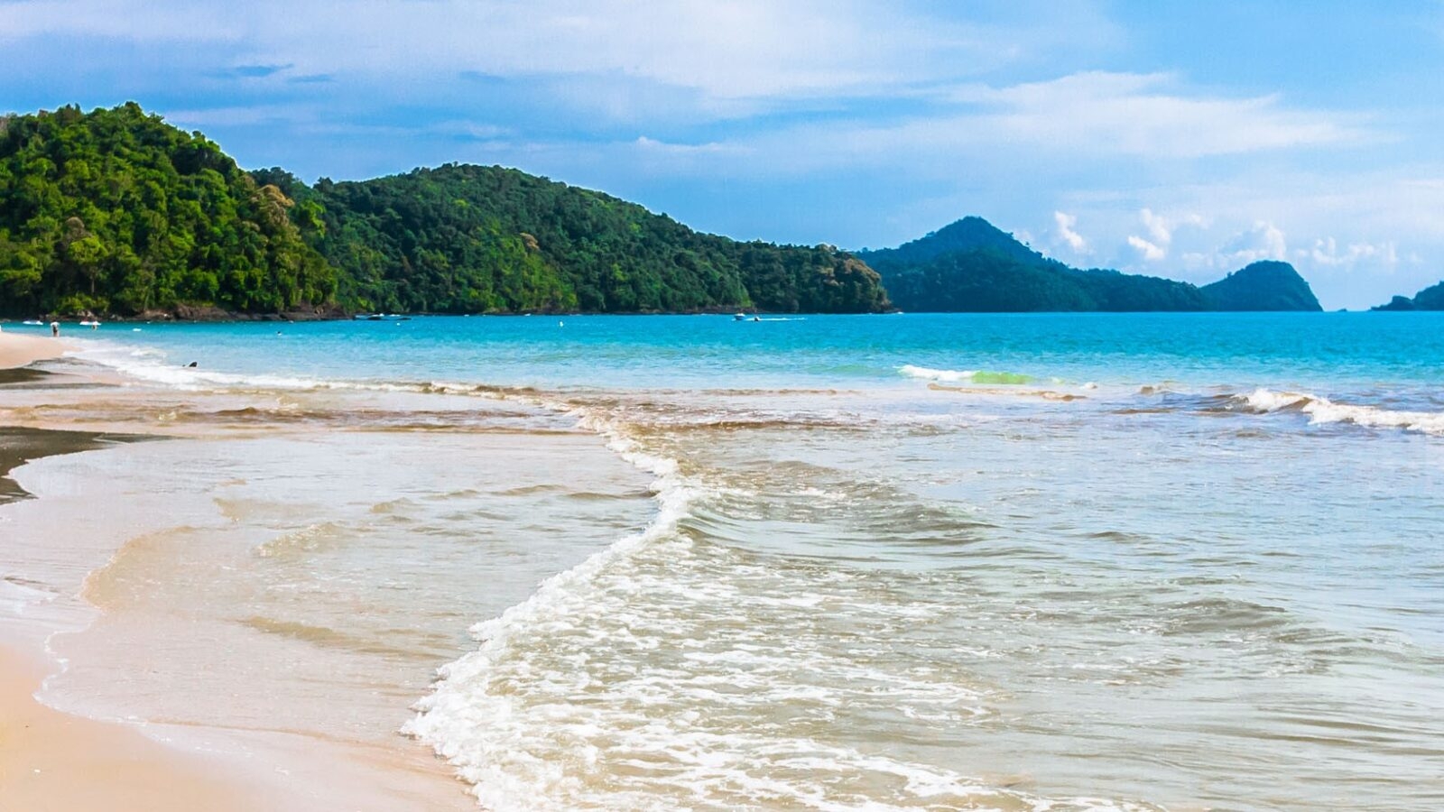 Waves lapping at the golden sands of an empty beach in Langkawi, Malaysia.