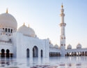 White marble courtyard and domes of the Sheikh Zayed Grand Mosque for luxury United Arab Emirates trips.