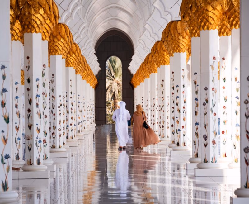 Couple walking through white marble arches with floral columns for luxury United Arab Emirates holidays.