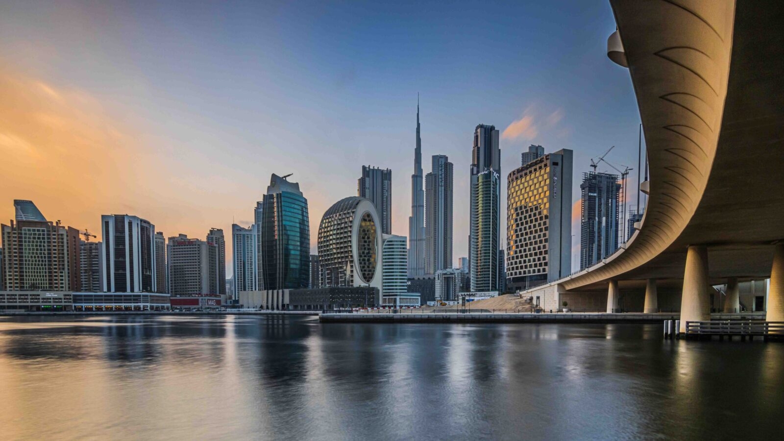 Dubai skyline at sunset featuring the Burj Khalifa and a curved bridge for luxury United Arab Emirates tours.