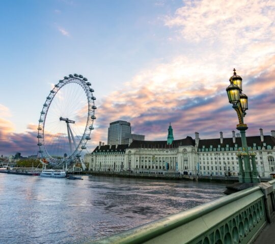 The London Eye and County Hall along the River Thames seen from Westminster Bridge at sunset.