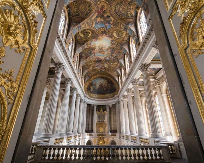 Grand baroque hall with gold carvings, white columns, and painted ceiling.