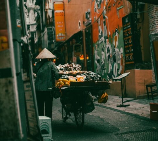 A street food vendor walking through the streets of Hanoi, with the food adorning their bike.