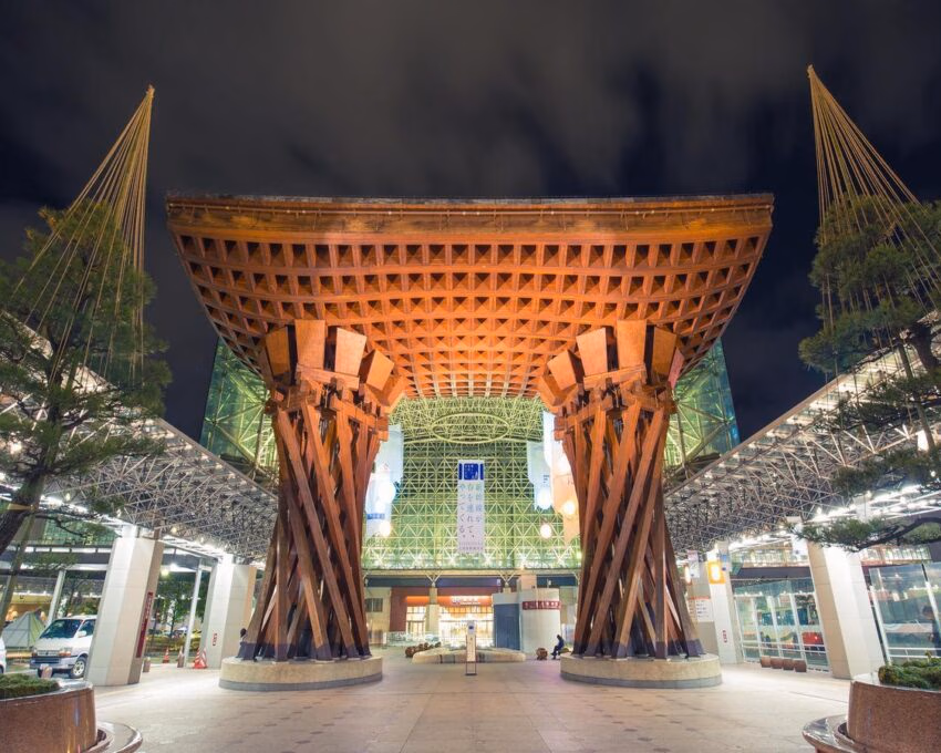 The illuminated wooden Tsuzumi Gate at Kanazawa Station at night.