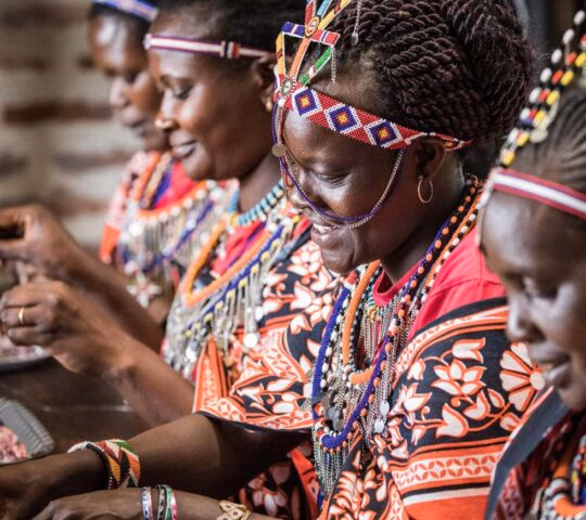 Women in traditional dress creating beadwork on a Great Migration luxury safari