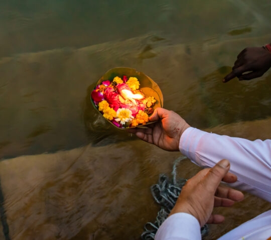 A devotee offering flowers to the Holy River at morning from a high angle