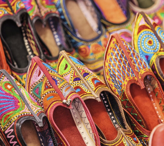 Traditional, brightly coloured shoes line a market stall