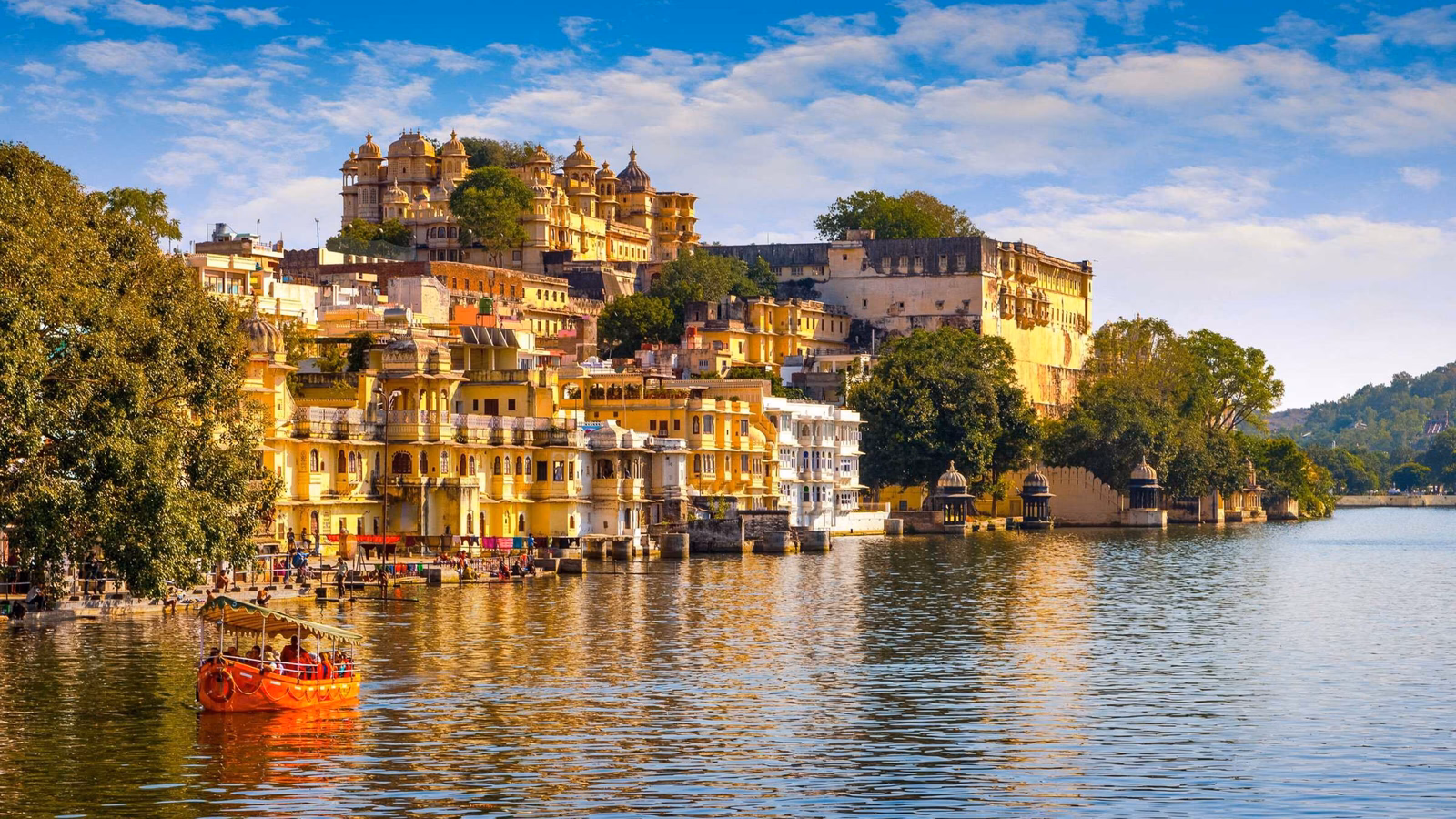 Udaipur city, with colourful buildings on the banks of a wide blue river