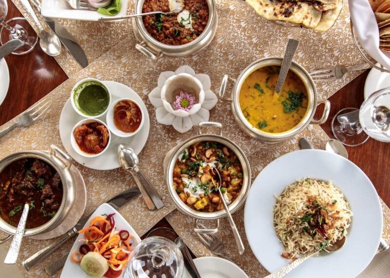 Aerial view of delicious Indian dishes, including curries, pickles, vegetables, rice, and breads