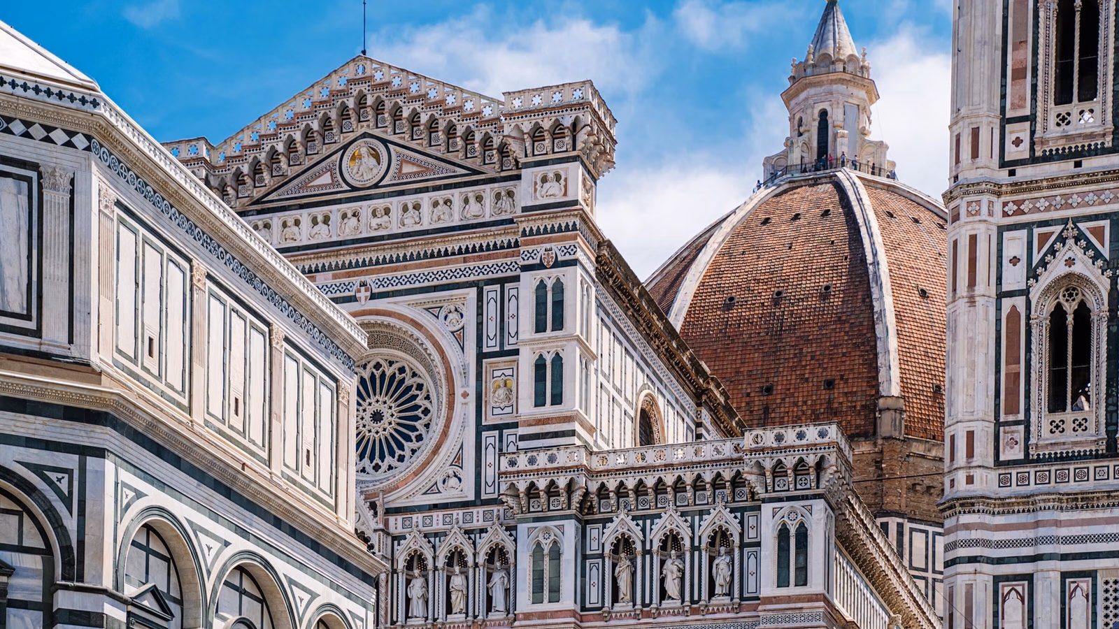 Detailed view of the marble facade and large red brick dome of the Florence Cathedral in Italy.