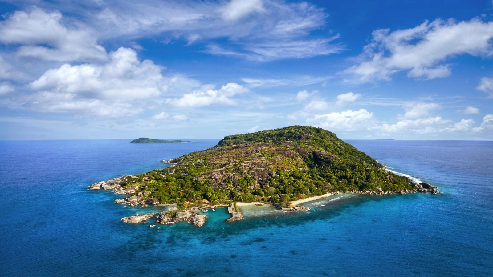 A small island with white beaches, coral reefs, and forests
