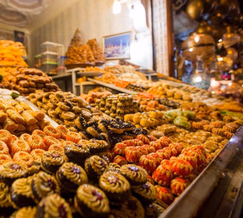 Close-up of various honey-soaked and chocolate-covered pastries arranged in a market display.