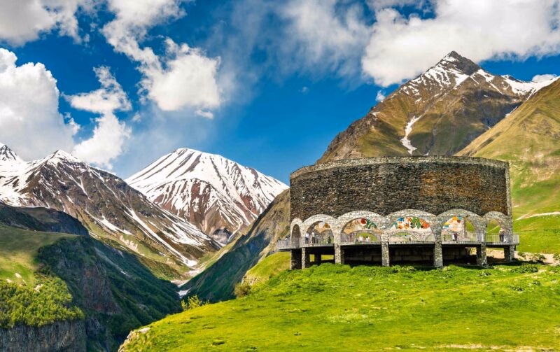A stone monument on a green hillside overlooking mountains during luxury Central Asia trips.