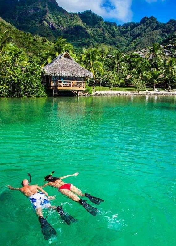 A couple snorkeling close to overwater villas in Bora Bora