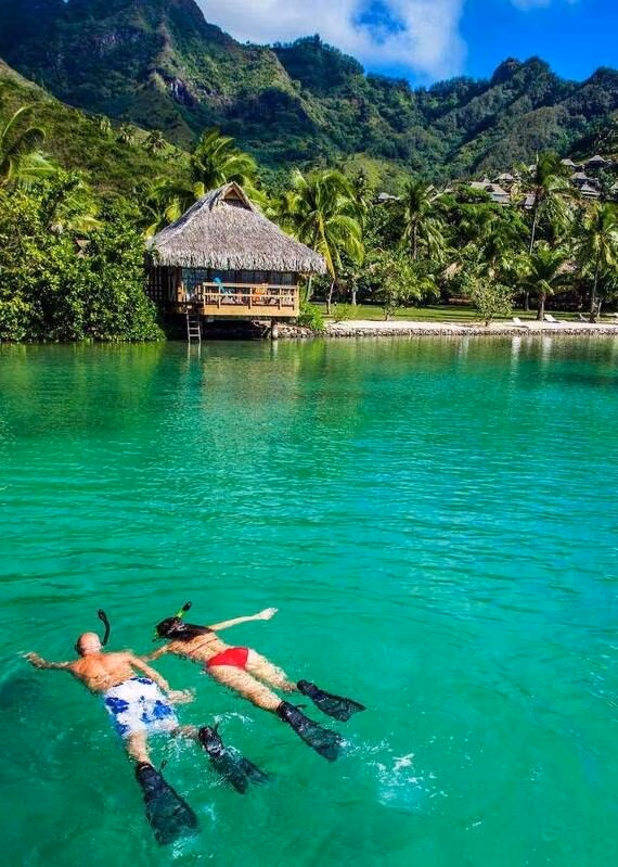 A couple snorkeling close to overwater villas in Bora Bora