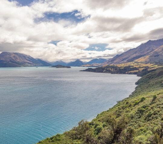 Winding close to the shoreline of Lake Wakatipu near Queenstown, New Zealand, a spectacular road leads to the small town of Glenorchy at the head of the lake through forested mountains