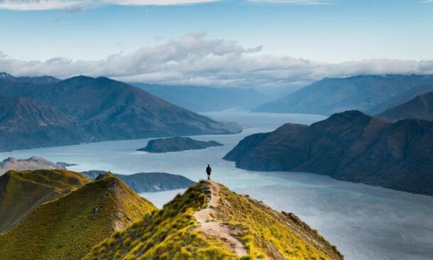 Roys peak mountain hike in Wanaka New Zealand. Popular tourism travel destination. Concept for hiking travel and adventure. Scenic view over lake from mountains peak. New Zealand landscape background.