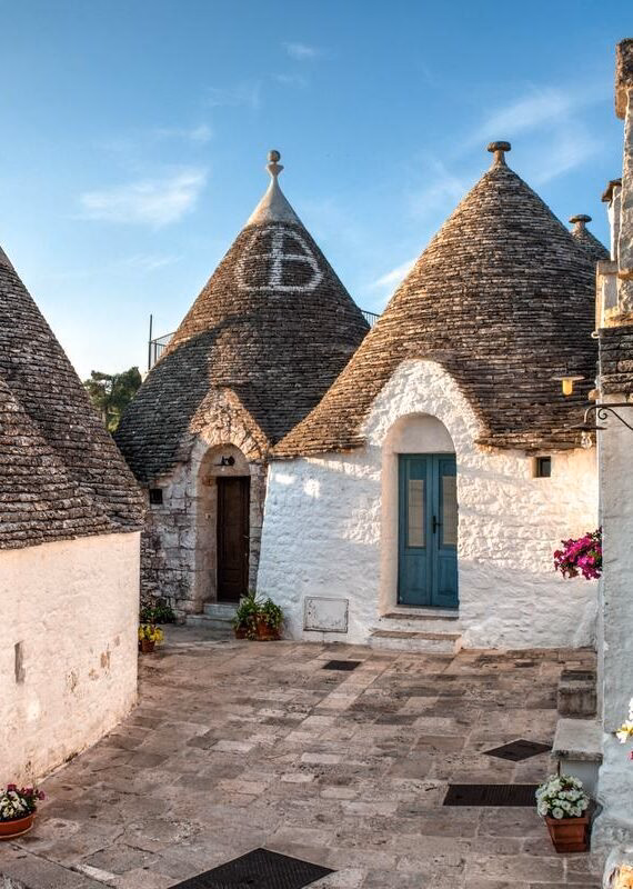 Conical roofs of traditional trulli houses in a sunny village during luxury Puglia vacations.