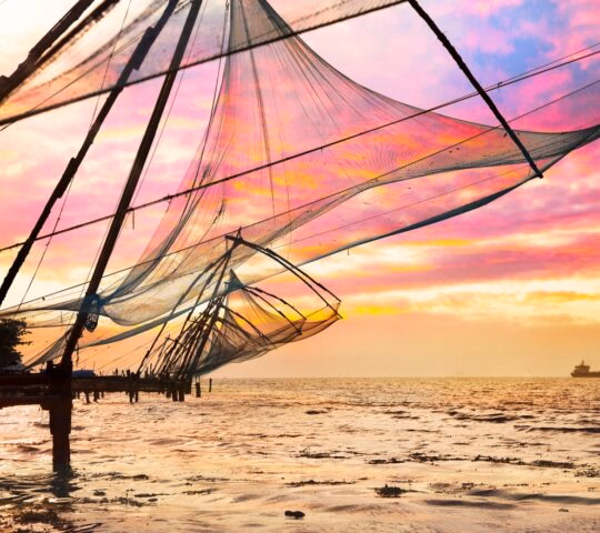 Chinese Fishing nets and small ship at dramatic sunset sky background in Kochi, Kerala, India