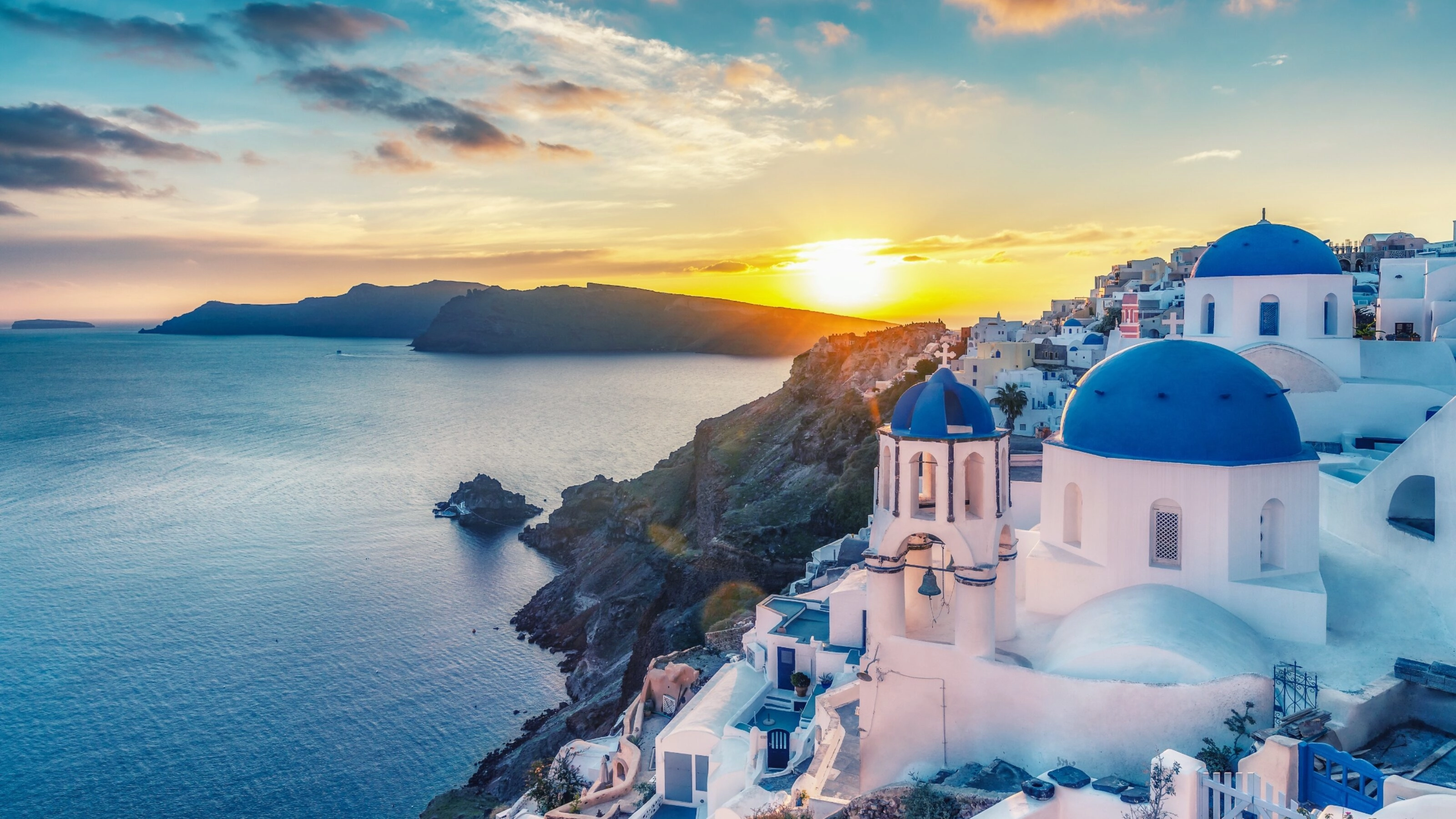 Beautiful view of Churches in Oia village, Santorini island in Greece at sunset, with dramatic sky.