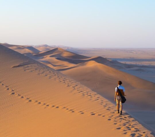 A man walking across the sand dunes in Sossusvlei, Namibia