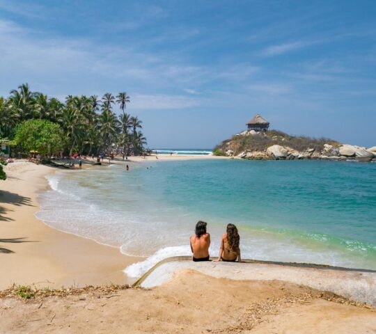 Back view of young couple sitting by the sea in Colombia, Tayrona